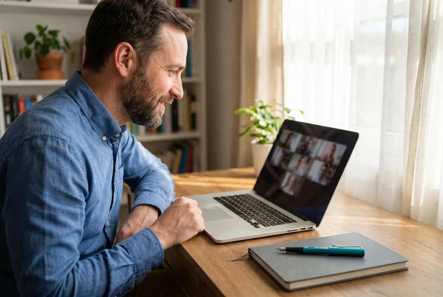 Psychiatrist listening intently during a telepsychiatry video call, a teal pen resting on his notebook Psychiatrist listening intently during a telepsychiatry video call, a teal pen resting on his notebook
