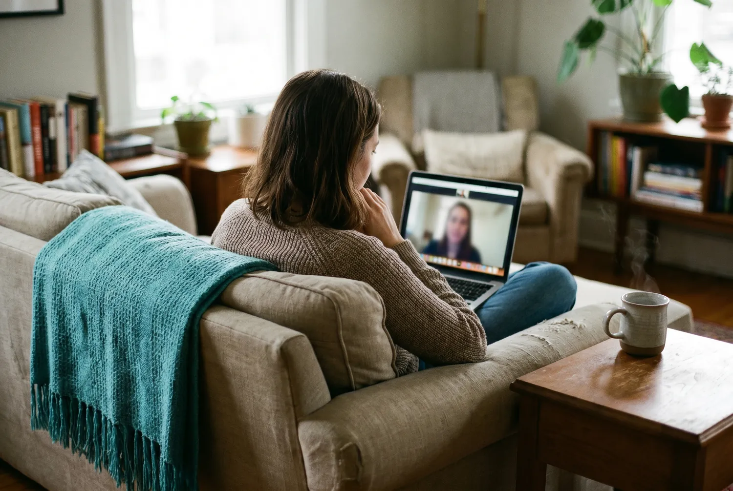 Woman on a sofa attending a telepsychiatry video appointment on her laptop Woman on a sofa attending a telepsychiatry video appointment on her laptop