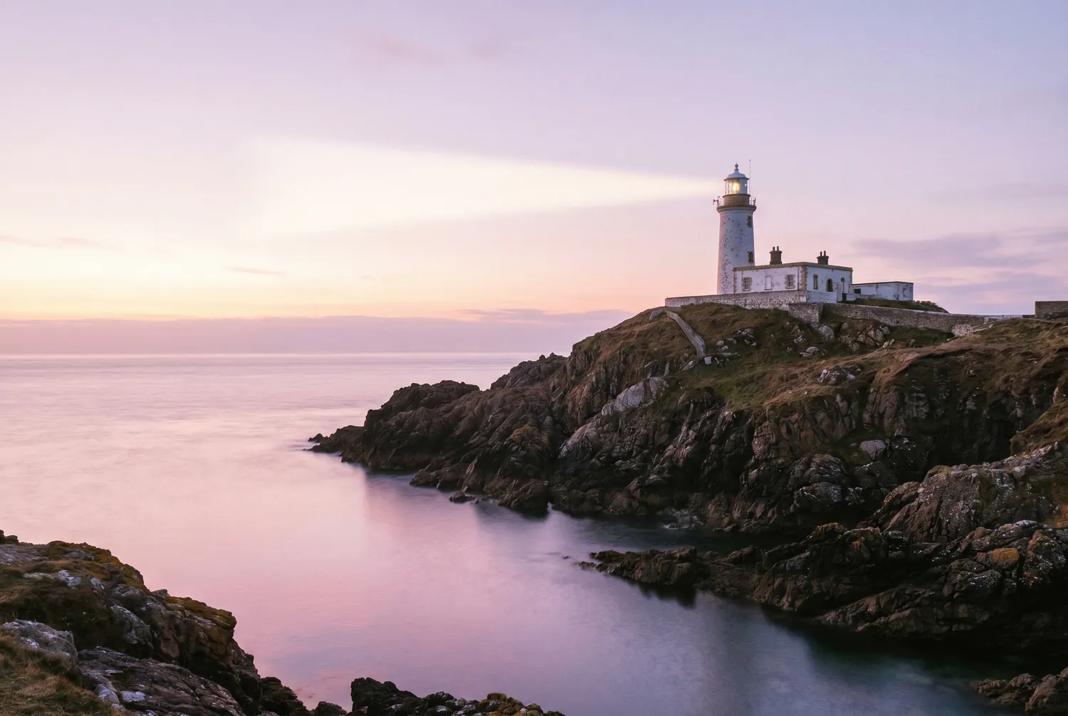 A white lighthouse on a headland at first light A white lighthouse on a headland at first light