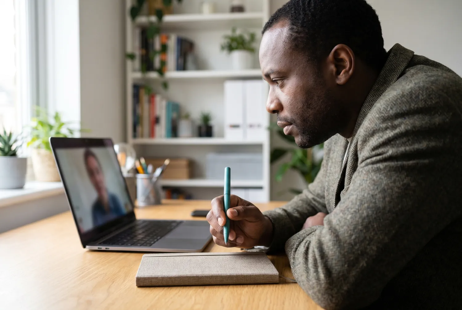 Psychiatrist listening intently during a telehealth session, holding a teal pen above a closed notebook Psychiatrist listening intently during a telehealth session, holding a teal pen above a closed notebook
